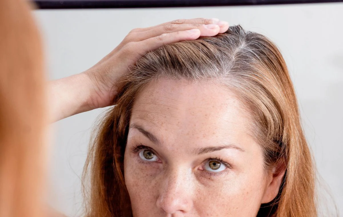 یک خانم درحالی که دارد موهای سفید خود را نگاه میکند